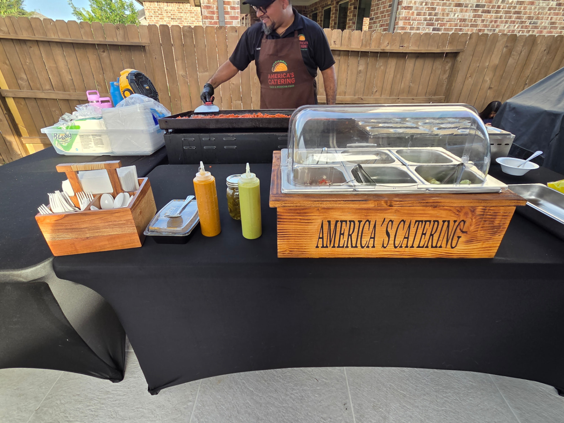 Catering table with salsas, utensils and covered toppings bar