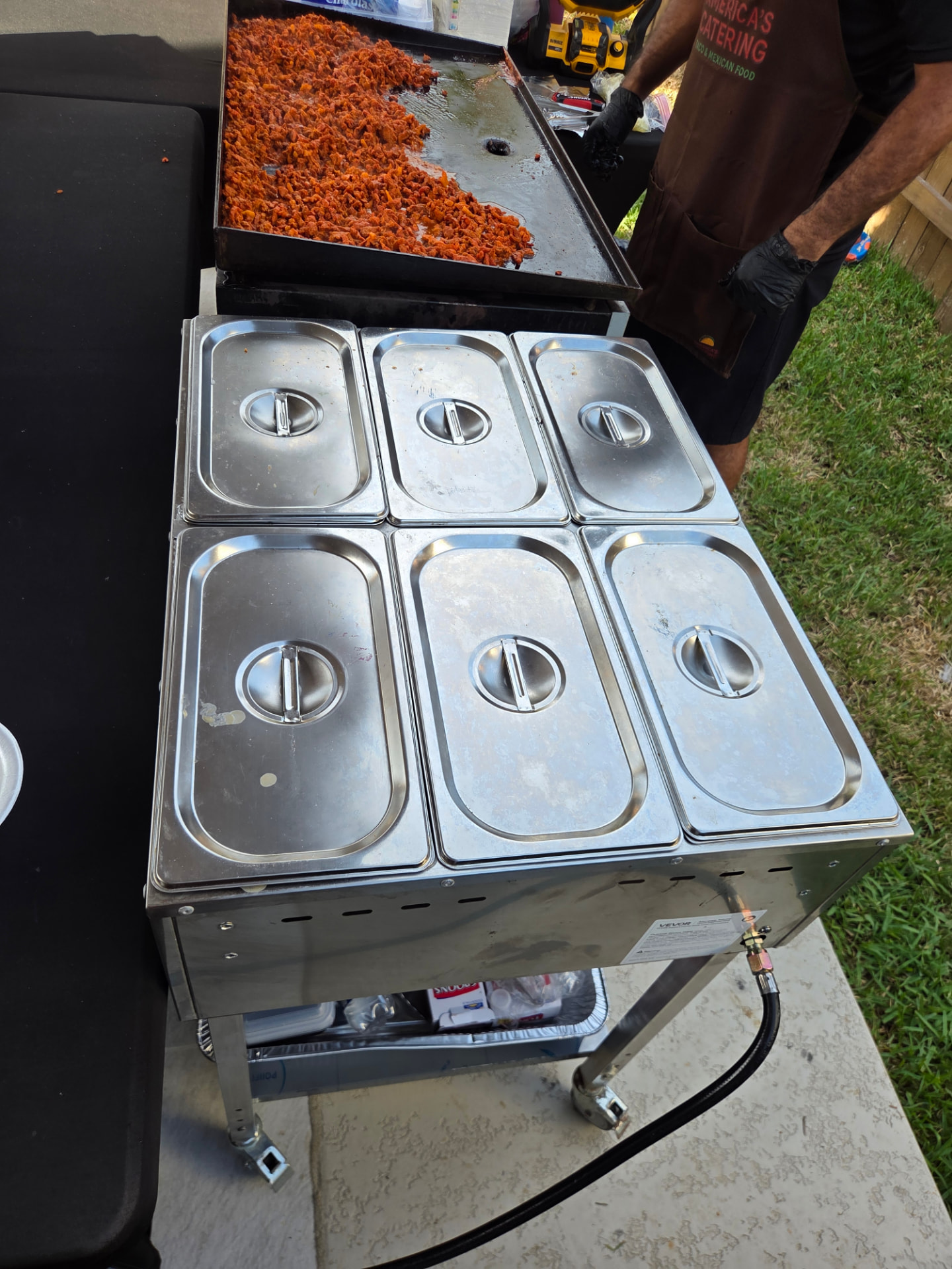 Steam table with six warming pans beside the taco griddle