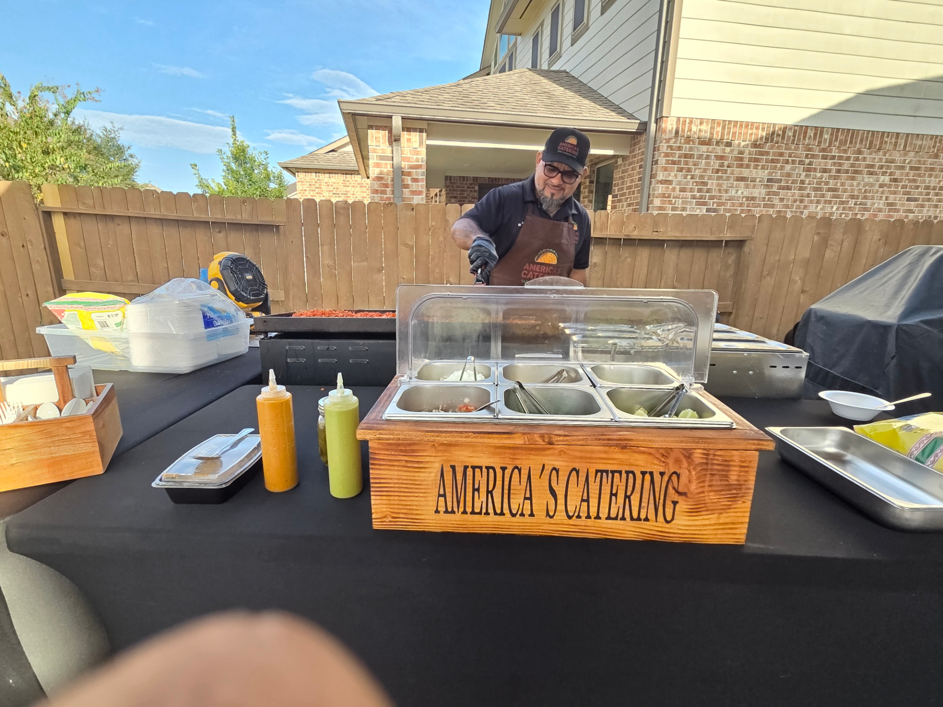 Full backyard taco catering setup with salsa bar and griddle